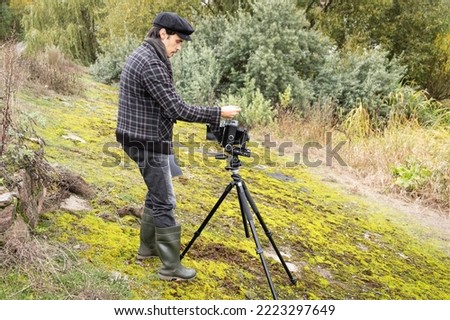 Photographer in the process of shooting on large-format retro camera. Shooting an autumn landscape with an old camera. Concept - old classic process, film camera. Selective focus. 
