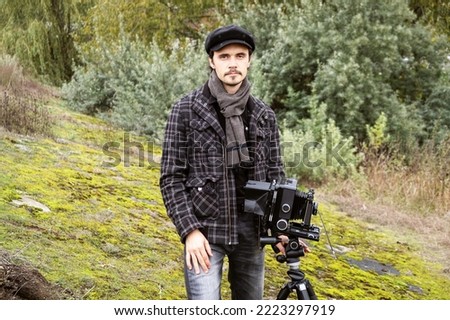 Portrait of photographer with wide angle retro camera. Looking at the camera. Shooting an autumn landscape with an old camera. Concept - old classic process, film camera, retro. Selective focus. 