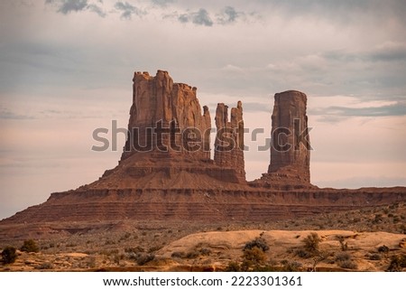 Beautiful view of rock formations at Monument Valley in desert. Geological features amidst landscape with cloudy sky in background. Famous tourist attraction in Navajo Tribal Park.