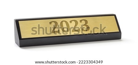  A name plate on a white background with the engraving 2023 Royalty-Free Stock Photo #2223304349