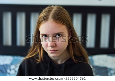A teenage girl is sitting on the bed, an emotion of sadness and despair. Cold season. Teenage problems. Royalty-Free Stock Photo #2223304361