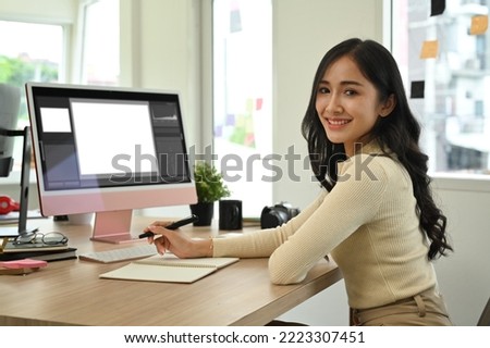 Confident female photo editors sitting in creative workplace front of personnel computer and smiling to camera