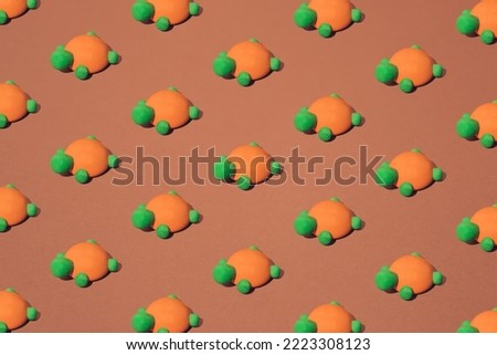 Orange green wooden turtle toy on a brown background. Minimal pattern.