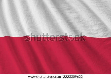Poland flag with big folds waving close up under the studio light indoors. The official symbols and colors in fabric banner