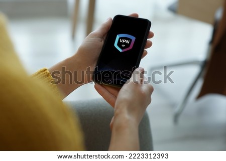 Woman using smartphone with switched on VPN indoors, closeup Royalty-Free Stock Photo #2223312393