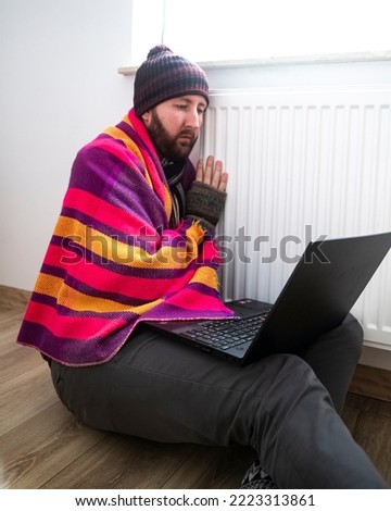 man freezes while working in office; cold at home; cold at work; energy crisis 2022; winter 2022; blackout; no heating; energy problems in europe; home office; gas crisis