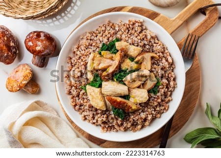 Boiled buckwheat with mushrooms porcini, turkey meat, spinach. Dinner table top view, healthy food concept. Royalty-Free Stock Photo #2223314763