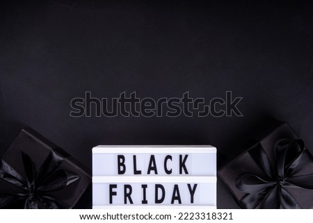 Black friday sale background. Simple black flat lay with sign "Black friday", gift boxes, shopping cart, laptop, tablet, headphones top view copy space. Online Black friday shopping concept
