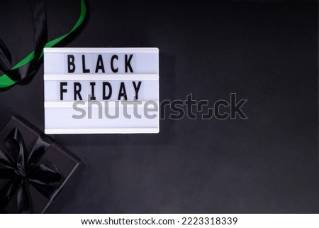 Black friday sale background. Simple black flat lay with sign "Black friday", gift boxes, shopping cart, laptop, tablet, headphones top view copy space. Online Black friday shopping concept