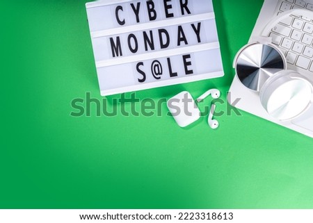 Cyber monday sale background. Simple bright green flat lay with lightbox "Cyber monday", gift boxes, shopping cart, laptop, tablet, headphones top view copy space. Online holiday shopping concept