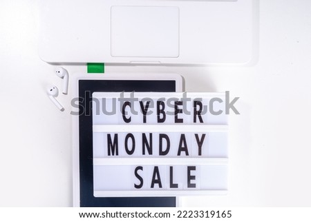 Cyber monday sale background. Simple white flat lay with lightbox "Cyber monday", gift boxes, shopping cart, laptop, tablet, headphones top view copy space. Online holiday shopping concept