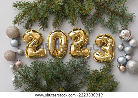 Figure 2023 made of balloons, fir branches and Christmas balls on grey background