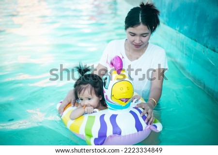Photo of adorable little girl with mom. Colorful unicorn inflatable ring swimming in a tropical ocean on summer vacation. High quality photo. copy space for text. 