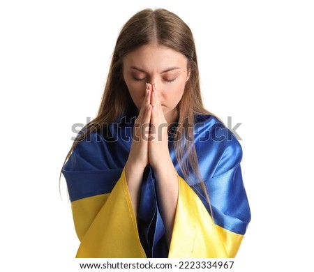 Young woman with Ukrainian flag praying on white background, closeup