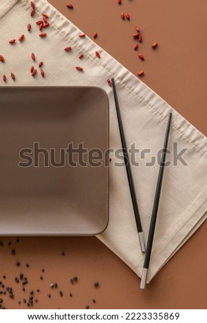 Table setting with chopsticks and scattered seeds on brown background