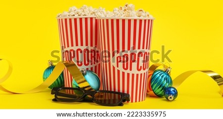 Buckets of popcorn with 3D glasses and Christmas balls on yellow background
