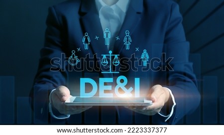 Businesswoman with tablet PC and virtual screen with abbreviation DE and I (diversity, equity, inclusion) on dark background Royalty-Free Stock Photo #2223337377