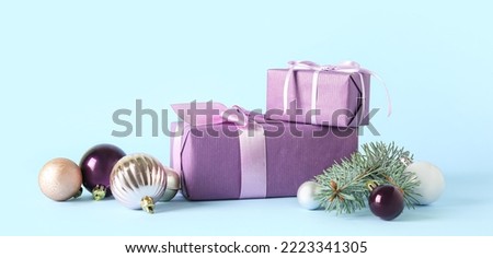Christmas gifts, balls and fir branch on light blue background