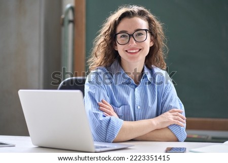 Young happy business woman sitting at work desk with laptop. Smiling school professional online teacher coach advertising virtual distance students classes teaching remote education webinars. Portrait Royalty-Free Stock Photo #2223351415