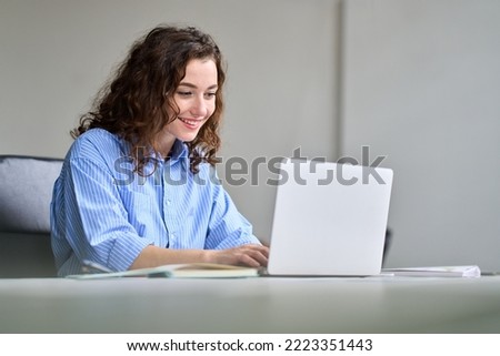 Young happy business woman company employee sitting at desk working on laptop. Smiling female professional worker marketer using computer in corporate modern office managing online data technology. Royalty-Free Stock Photo #2223351443