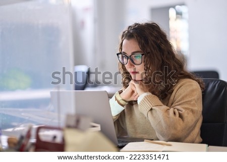 Young serious busy professional business woman employee or student using laptop watching online webinar or training web course, looking at computer, thinking, elearning, doing research concept. Royalty-Free Stock Photo #2223351471