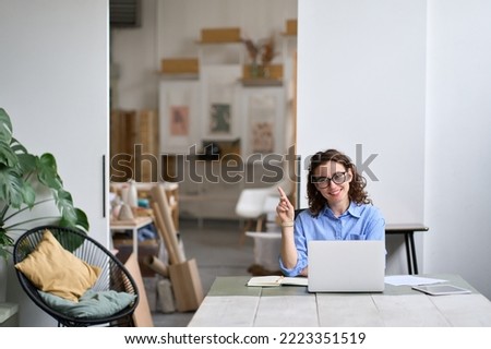 Young happy business woman company employee sitting at desk working on laptop. Smiling female professional designer or student using computer in corporate office pointing advertising coworking space. Royalty-Free Stock Photo #2223351519