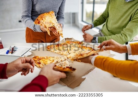 Cropped picture of the businesspeople taking slices of pizza for lunch break at the office.