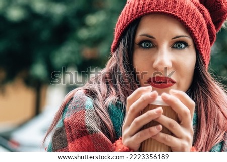 Beautiful smiling young woman in warm clothing with cup of hot tea coffee or punch. The concept of portrait in winter snowy weather