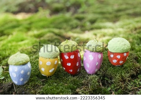 Colorful painted acorns with polka dot pattern on green moss outdoors, closeup