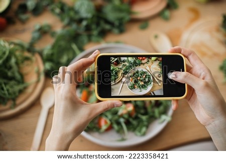 Woman hands take phone photo of food lunch or dinner. Vegetable salad, avocado, arugula tomatoes. Smartphone photography for social networks. Raw vegan vegetarian healthy food. Royalty-Free Stock Photo #2223358421