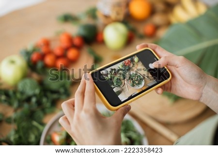 Woman hands take phone photo of food lunch or dinner. Vegetable salad, avocado, arugula tomatoes. Smartphone photography for social networks. Raw vegan vegetarian healthy food.