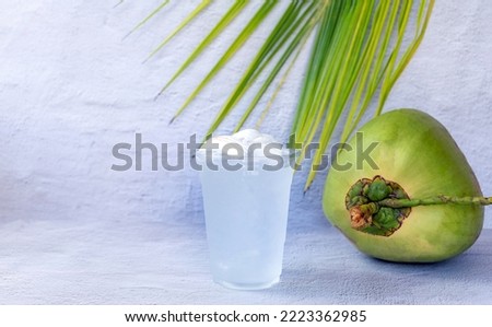 Ice coconut water drink in a plastic glass and coconut on white background