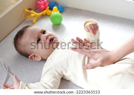 Masseur massaging the tummy of the baby during colic. Mother massaging infant belly, kid laughing. Royalty-Free Stock Photo #2223363153