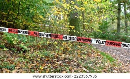A cordon with red and white police tape and a notice of a police cordon off an area in a forest in autumn in a German forest Royalty-Free Stock Photo #2223367935