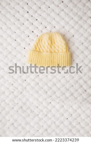 A small knitted warm hat on a white soft blanket