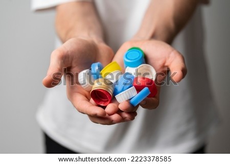 recycling plastic, person holds color bottle caps Royalty-Free Stock Photo #2223378585
