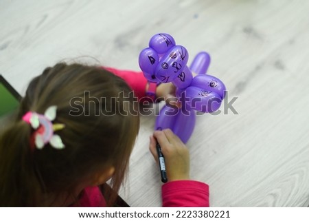 Little cute girl is coloring a ball toy. Encouraging the child to develop in the artistic field. Top view