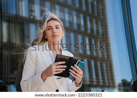 Gorgeous  blonde exhausted caucasian young woman in white suit, holding diary looking aside. Tired lawyer disappointed after failure, financial troubles , business breakdown. Upset businesswoman.