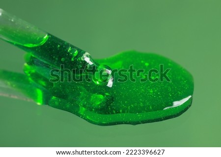Dripping serum from pipette on mirror, closeup. Toned in green