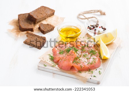 salted salmon, bread and ingredients on a wooden board, horizontal