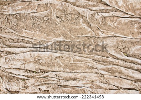 Aged white foil crumpled and covered with sand