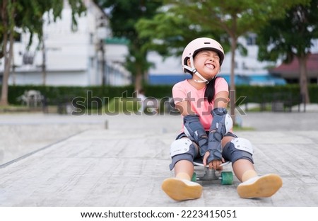 asian child skater or kid girl smile playing skateboard or sitting laugh on surf skate and enjoy fun in skate park for extreme sports exercise to wear helmet elbow wrist knee support for body safety Royalty-Free Stock Photo #2223415051