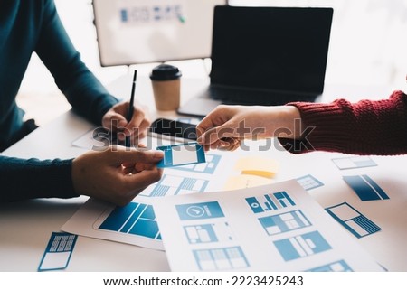 Ux developer and ui designer brainstorming about mobile app interface wireframe design on table with customer breif and color code at modern office.Creative digital development agency