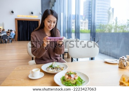 Woman use cellphone to take photo on her meal in coffee shop