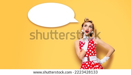 Studio portrait image of thinking woman in red pin up dress. Blond pinup thougthfull girl on yellow background. White empty blank speech sign bubble, having idea Mockup, ready for your design. Ad conc