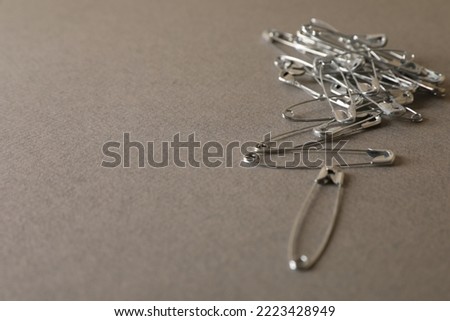Safety pins on grey textured background, closeup. Space for text