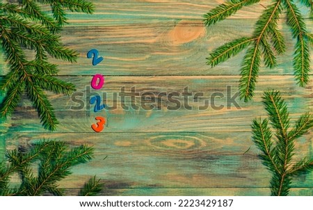 Christmas wooden background with branches and the date 2023.
