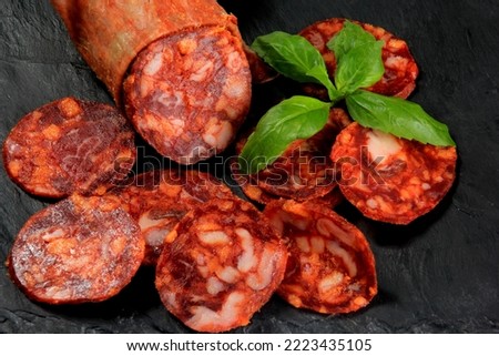 Spanish pork chorizo salami sausage slice on black stone plate. Chorizo iberian extra sausage slice