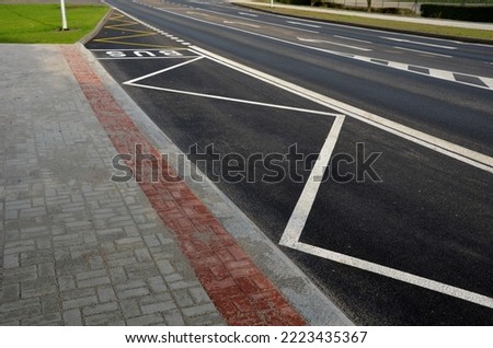 bus stop consisting of a reserved place with the word bus. Horizontal traffic sign white lines. The concrete curb is rounded due to damage to the sidewall of the tire. paving for the blind from red 