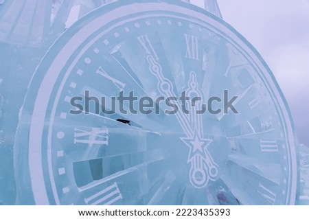 Celebrating the New Year in winter. Christmas and winter. A sculpture carved out of ice. Background of frozen ice decoration for Christmas. A watch made of ice. The dial of the ice clock.